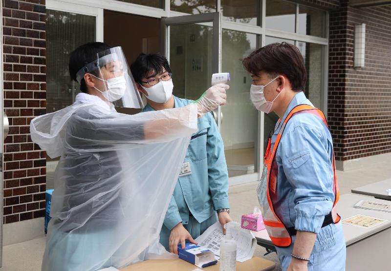 受付で体温の計測を受ける避難者役の職員(右)