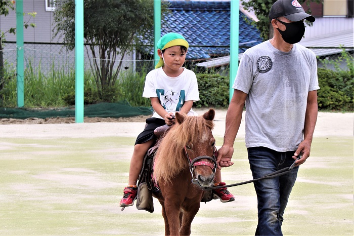 子どもがポニーに乗っている写真