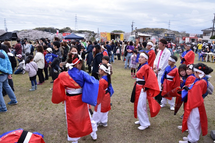 祭り会場でキッチンカーなどさまざまな催しをそれぞれ楽しむ人々の写真