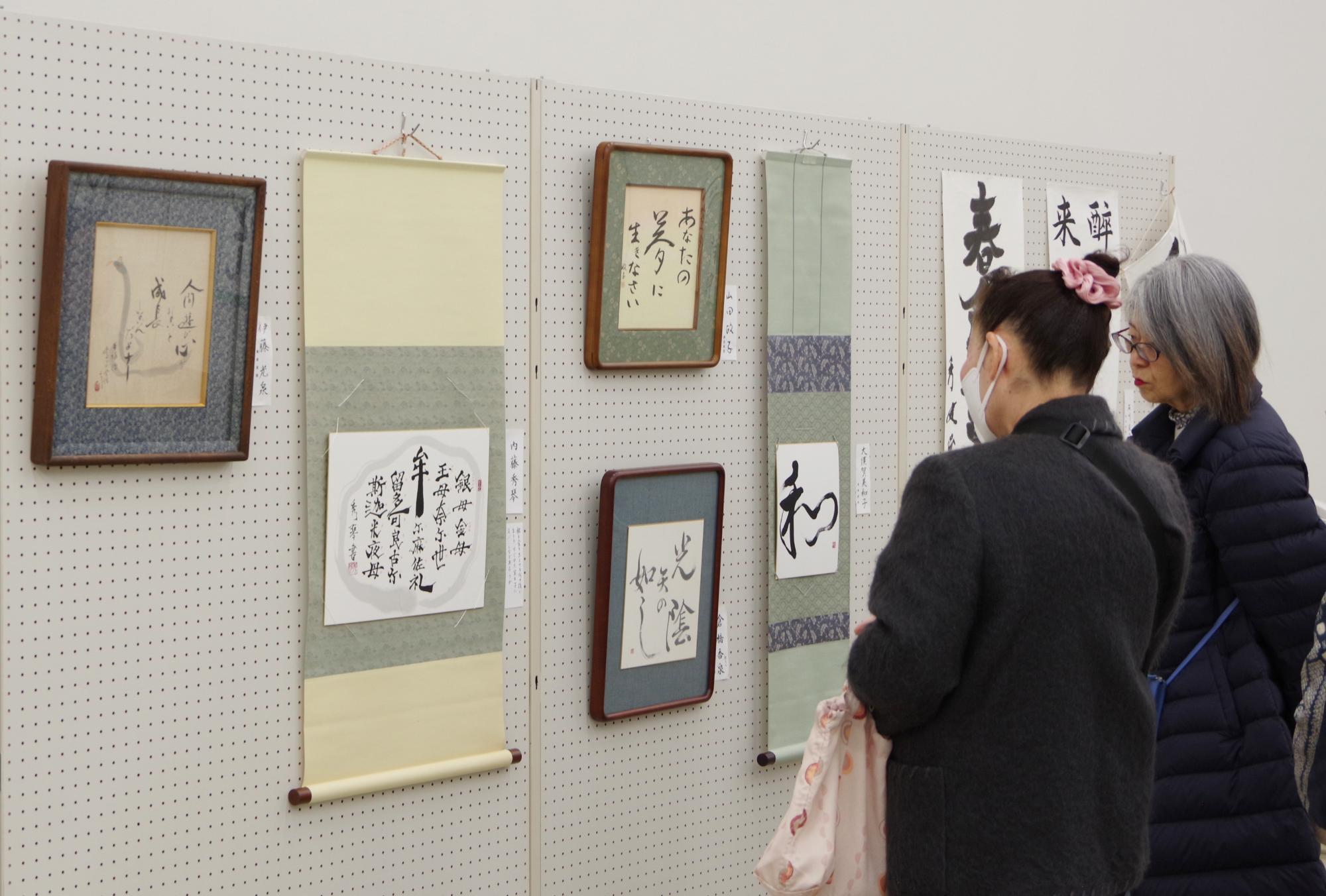 書道連盟理事の作品を鑑賞する来場者の写真