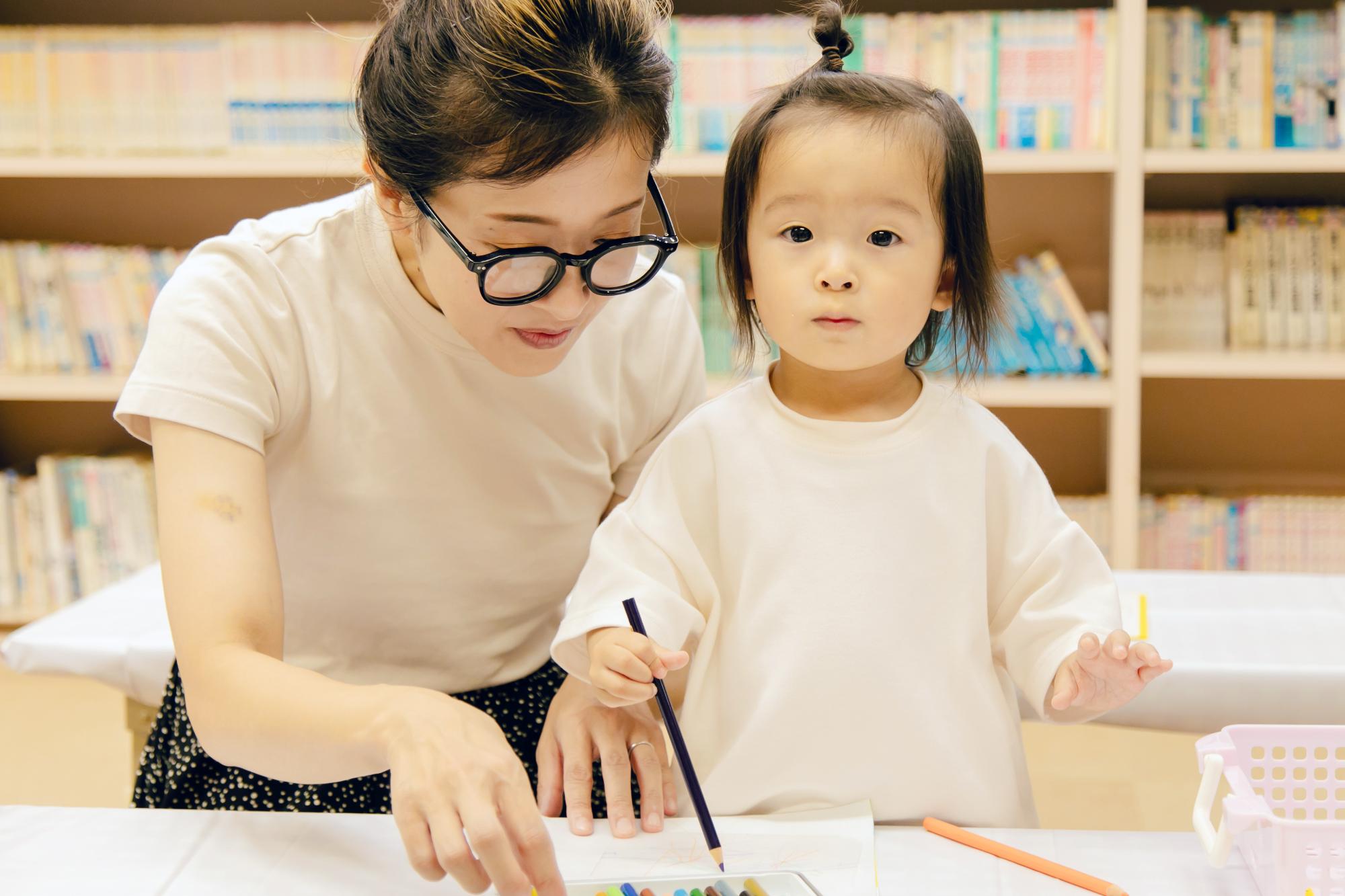 こどもがお母さんと一緒に色鉛筆でイラストを描いている様子の写真その2