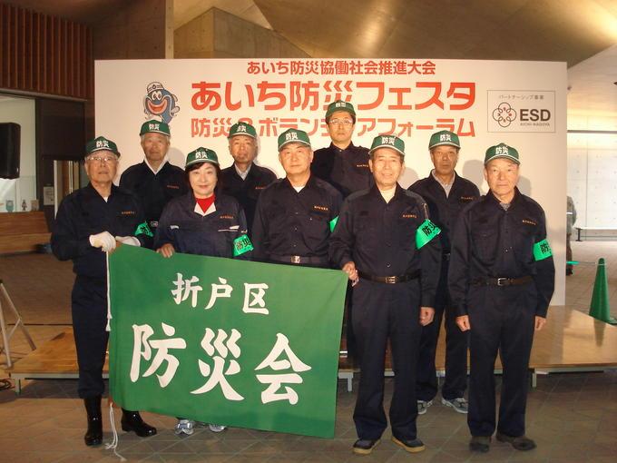 折戸区防災会と書かれた緑の旗を持つ、折戸区自主防災会の皆さんの写真