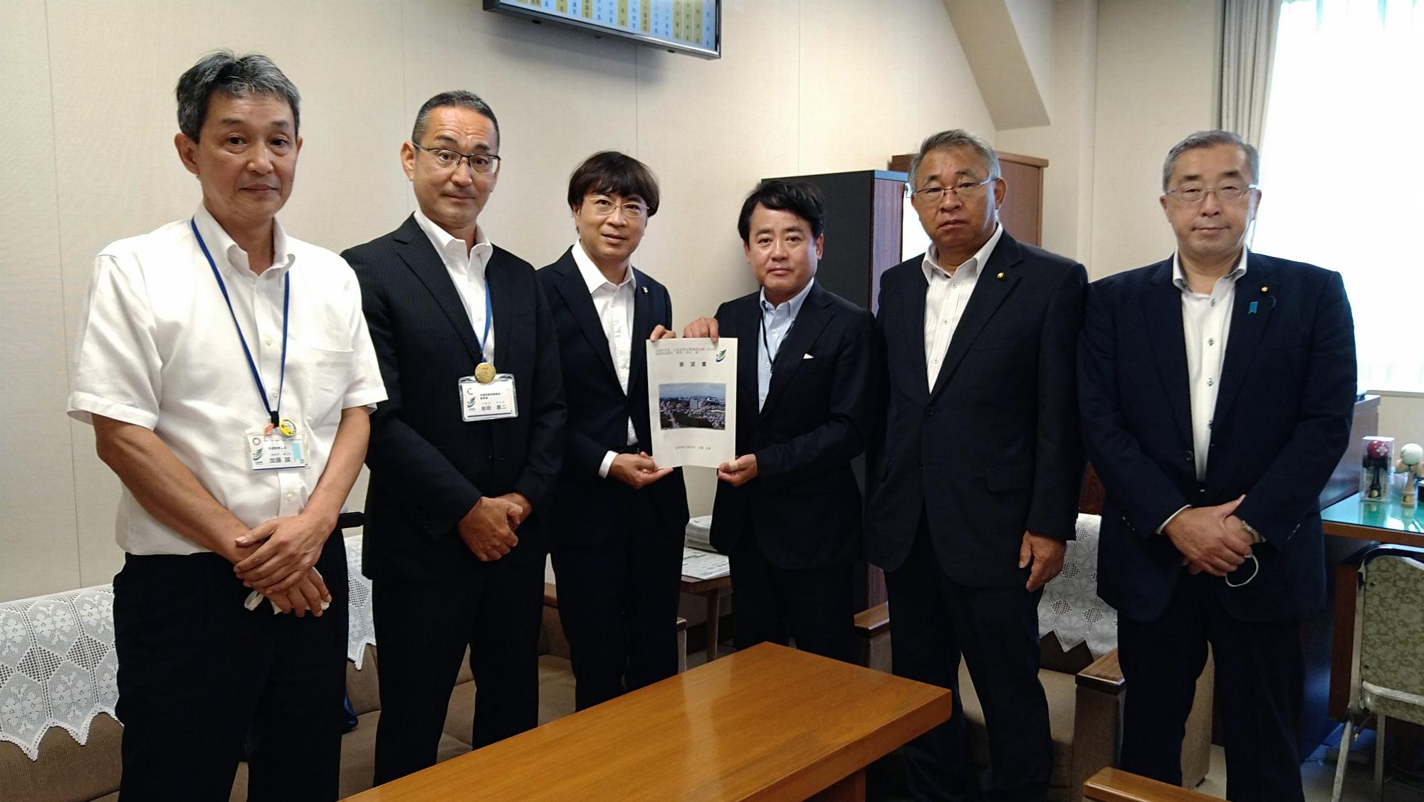文部科学省大臣官房文教施設企画・防災部の野沢和也施設助成課長に要望書を手渡す近藤市長ら