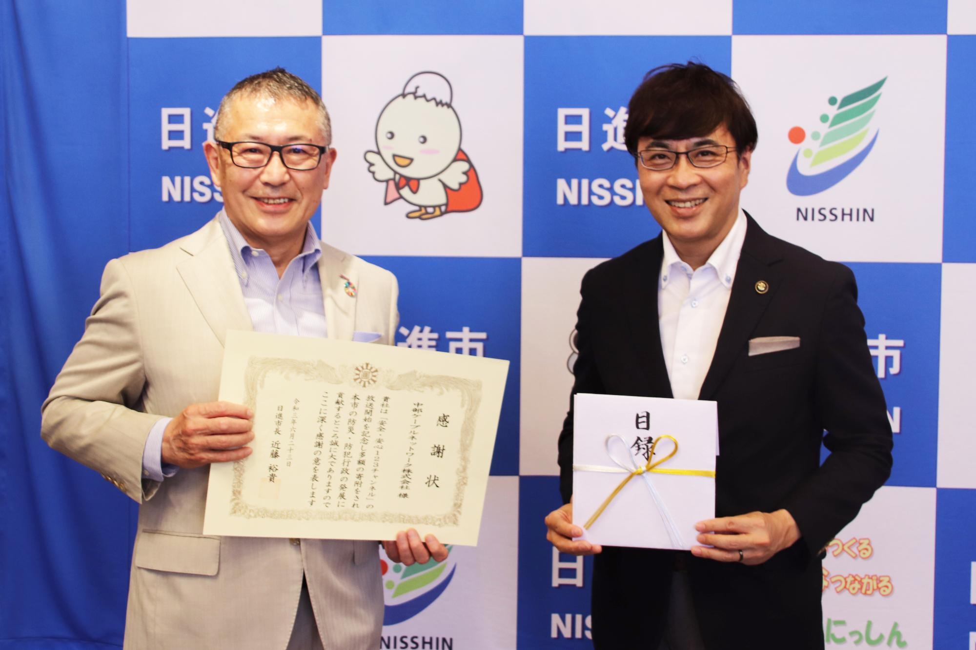 寄附の目録と感謝状を手に記念撮影をする近藤市長ら