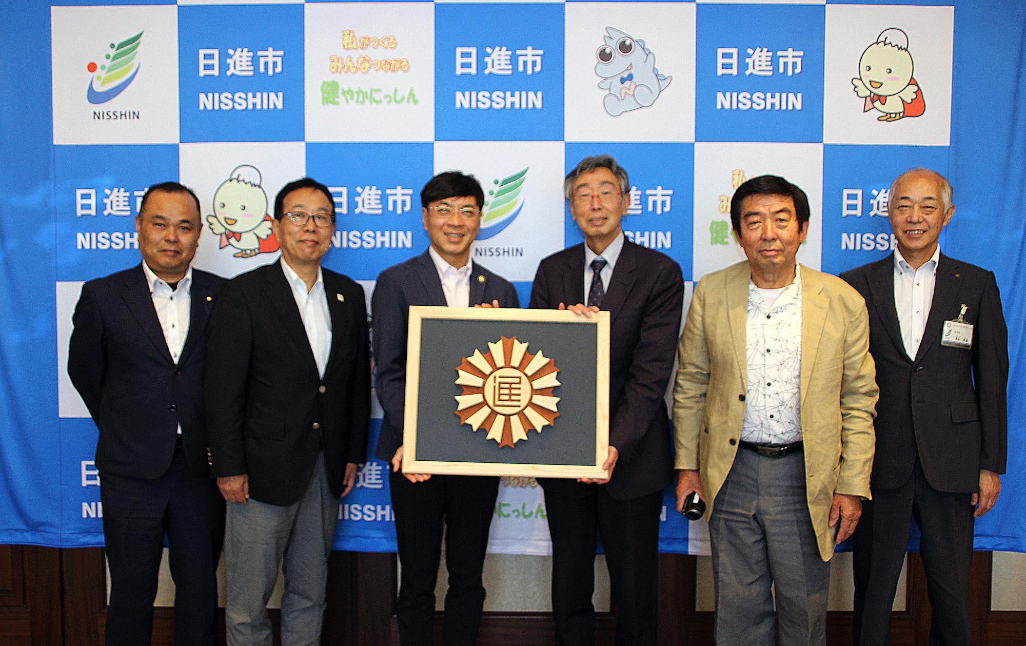 市章を寄贈いただいた岡本様、他の皆様と写真を撮る近藤市長と青山副市長
