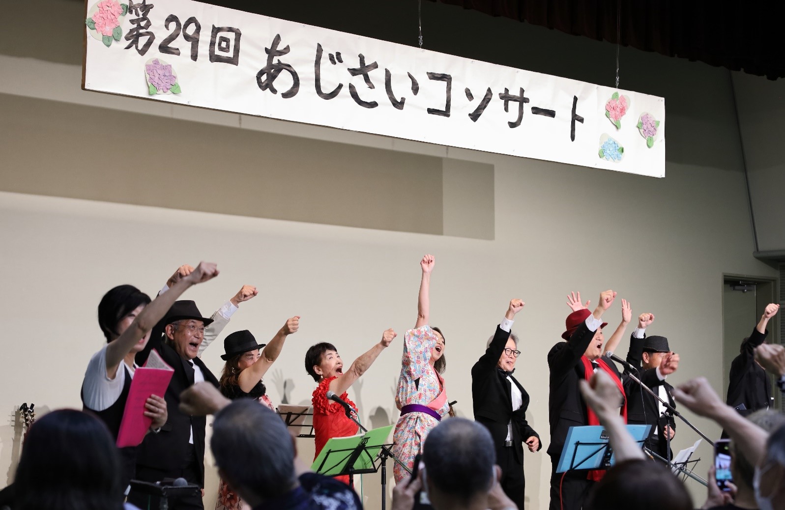 みんなで手を上げるポーズをとりながら昭和歌謡を歌う参加者の写真