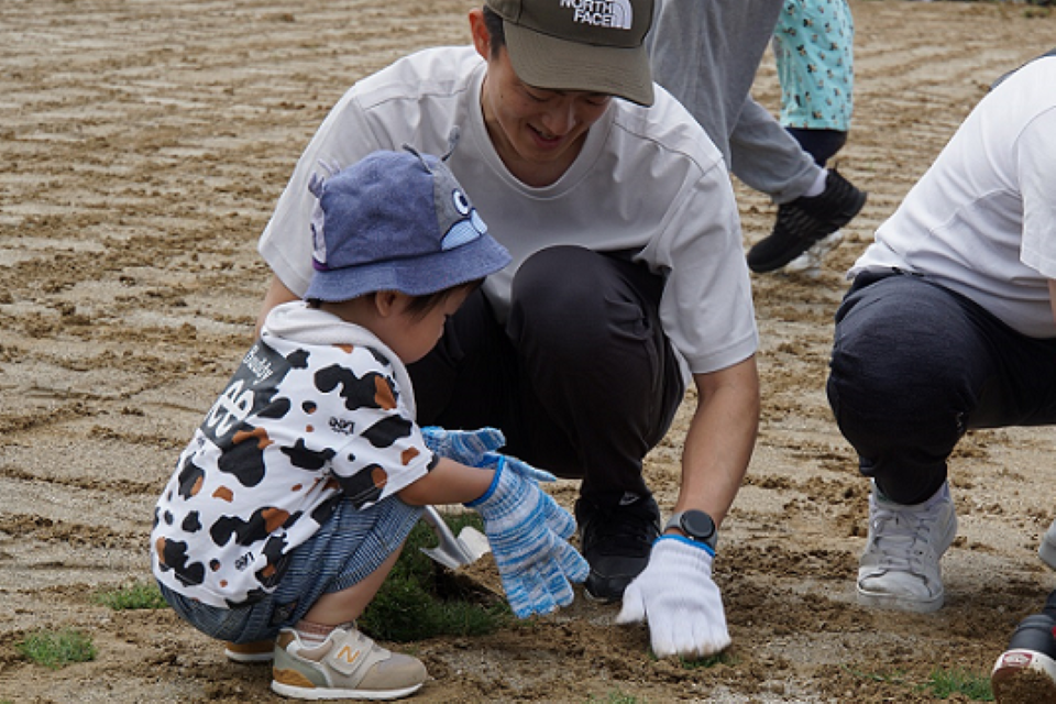 楽しそうな様子で芝植えのイベントに参加する親子の写真