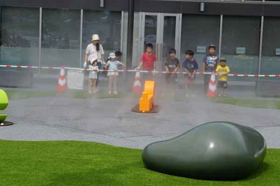 イベント後にミストで涼む参加者の親子と子どもたちの写真