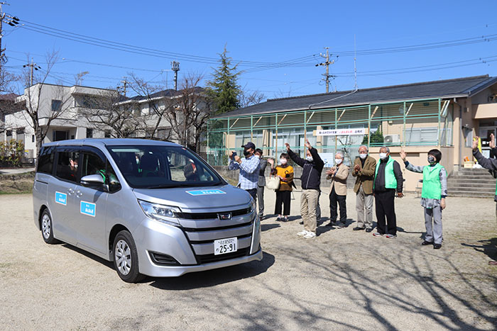 支援車が出発するのを見送る関係者たち