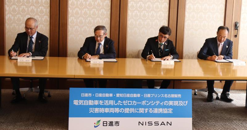 協定締結式で協定書にサインする列席者