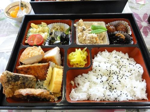 色とりどりの副菜が詰められ、ご飯には黒ごまがかけられた美味しそうな弁当の写真