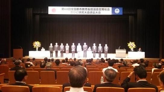 全国都市教育長協議会定期総会並びに研究大会にて壇上に複数名が横に並んでいる写真