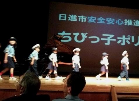 日進市安全安心推進大会にて子供たちが警察服を着て壇上を歩いている様子の写真
