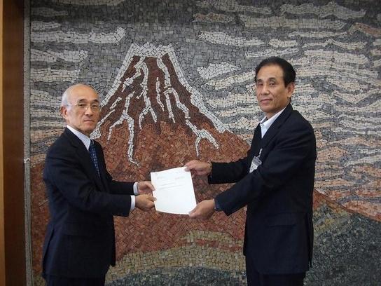 第4回日進市教育振興基本計画策定委員会が開催され、中野靖彦委員長より教育長へ基本計画見直し案が提出される様子の写真