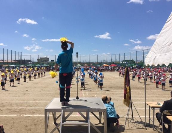 運動会にて壇上でポンポンをもっている先生とポンポンをもって生徒が踊っている写真