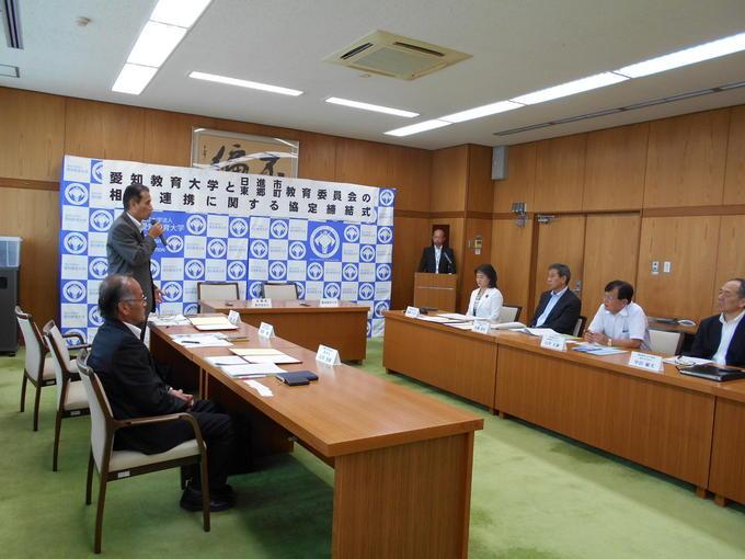愛知教育大学と日進市の相互連携に関する協定締結式が同大学で行われマイクをもって話をしている方と机を挟んで話をきいている人たちの写真