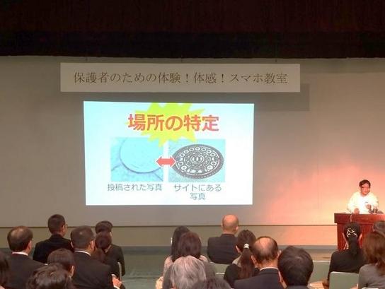 日進市民会館にて「保護者のための体験!体感!スマホ教室~危険を知って安全に使おう~」が開催されプロジェクターを使って演説をしている写真