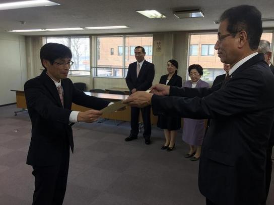 日進市内の小中学校において長年事務職員として勤務し、事務改善に尽力されました伊藤利明さんへ、教育長より賞状を贈呈している写真