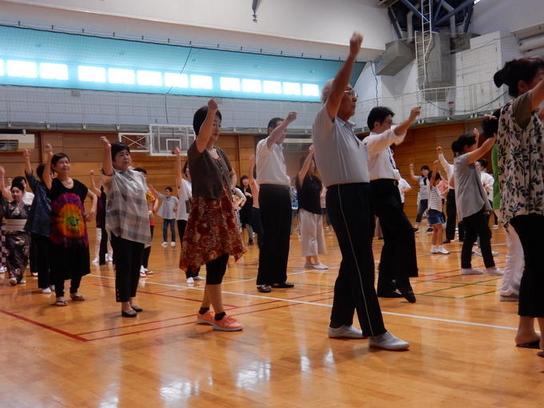 体育館で男女が盆踊りをしている写真