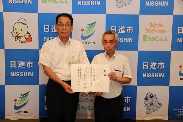 日進市役所にて米野木区画整理組合の寄附目録贈呈式が行われた際の表彰状を持った男性2名の写真