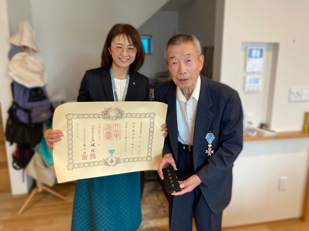 受賞者と副教育長で症状と勲章を飾って記念写真