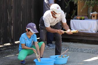 子どもが竹製の水鉄砲で遊んでいる写真