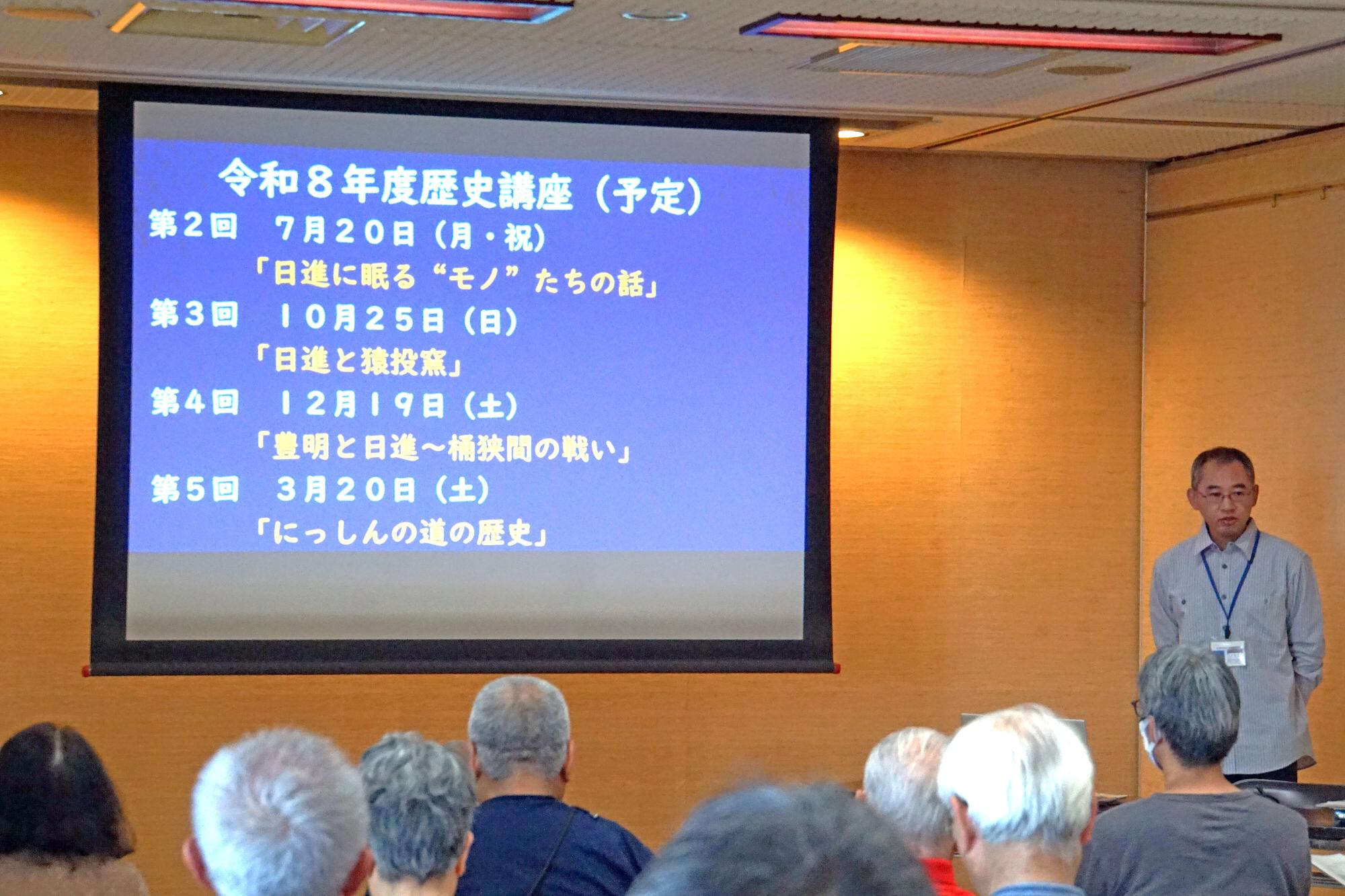 スライドを用いて今後の予定を解説している講師の写真