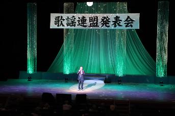 ライトを浴びながら歌う出演者