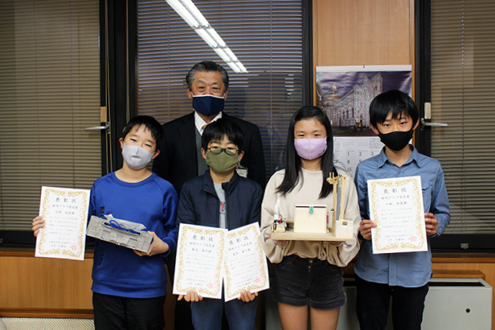 作品と表彰状を手にする受賞者たちと久保田教育長