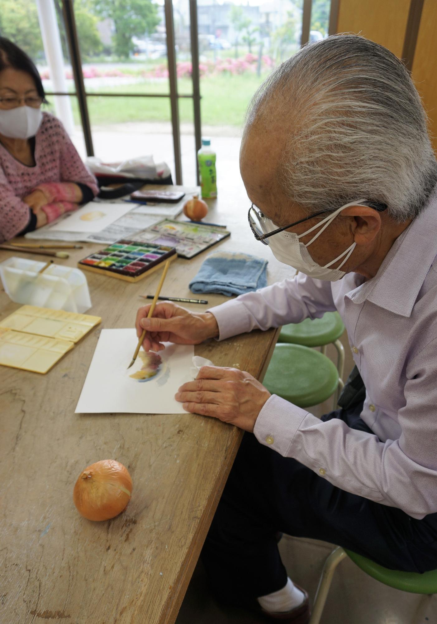 色の塗り重ねを見せる幸田さん