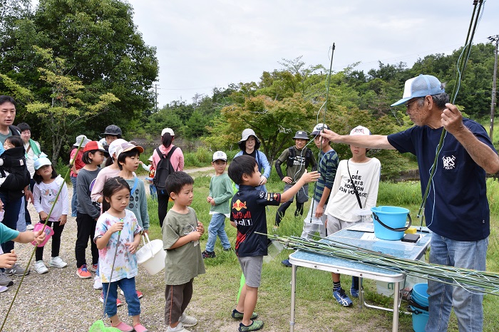 子どもたちが開催者から釣り竿を受け取っている写真
