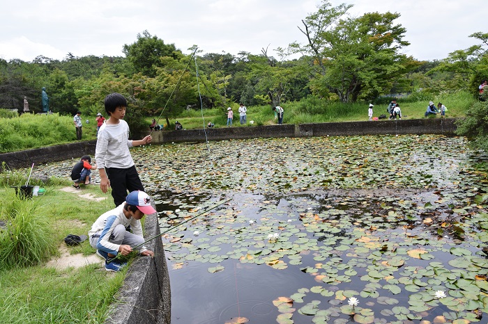 参加者が池に釣り竿を垂らしている写真