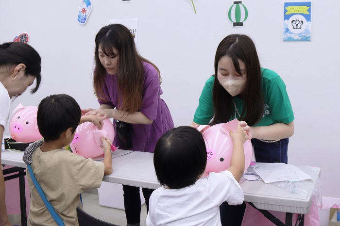 風船でブタを作る子供たちの写真