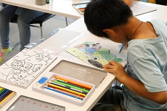 子どもが紙芝居の下絵に色を塗っている写真