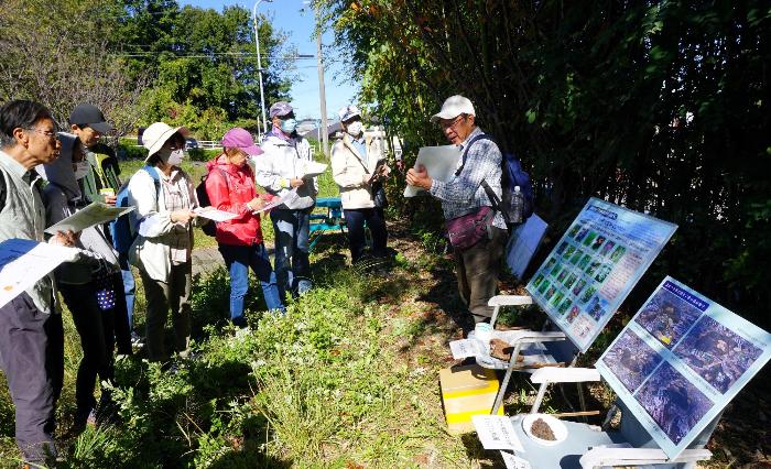 樹木医であり梨子ノ木自然観察会の代表でもある堀透さんが参加者に写真などを示しながら草木の種類の説明をする写真