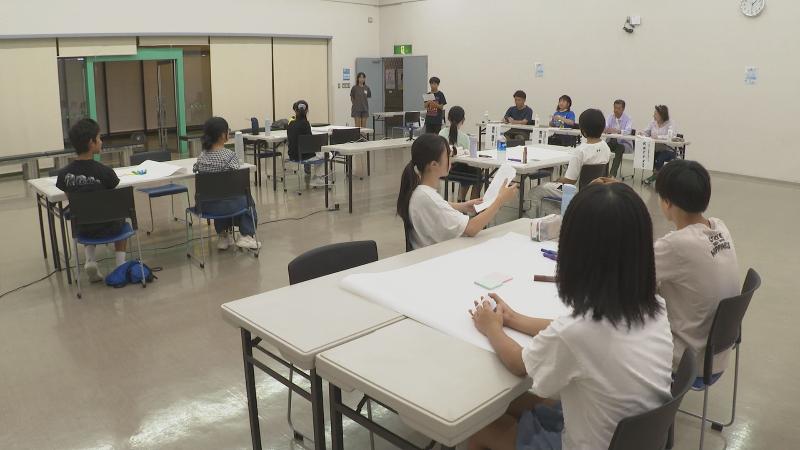 イベントの様子。子ども達がマイクを持って、疑問を4人の大人たちに問いかけています。