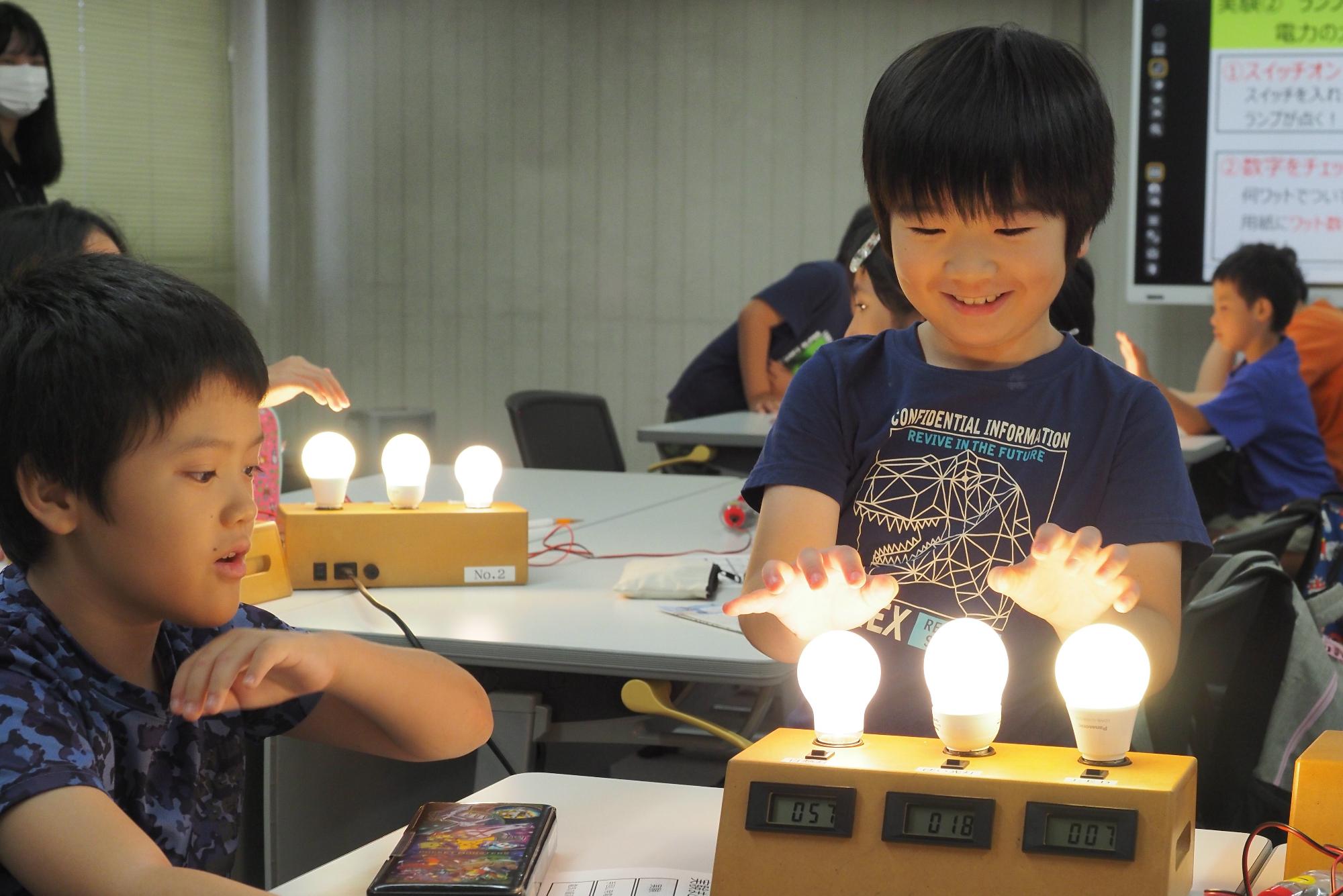 点灯したランプに手を近づける子どもの写真
