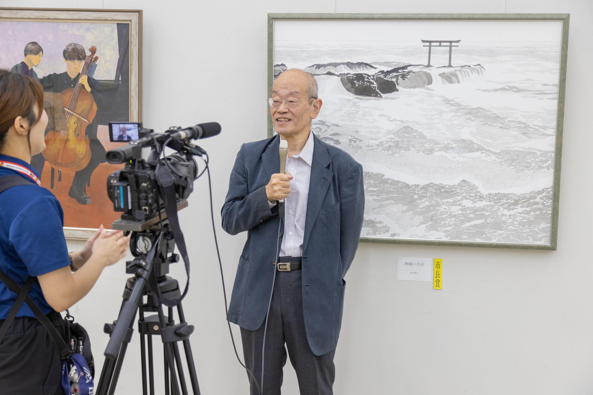 テレビの取材に答える制作者とその作品の写真