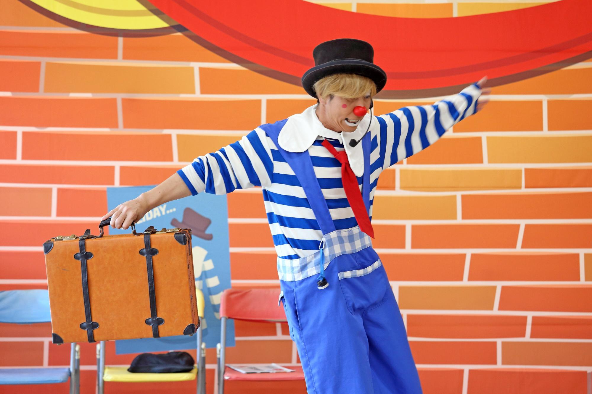 カバンを使ったパントマイムの演技を披露するピエロの写真