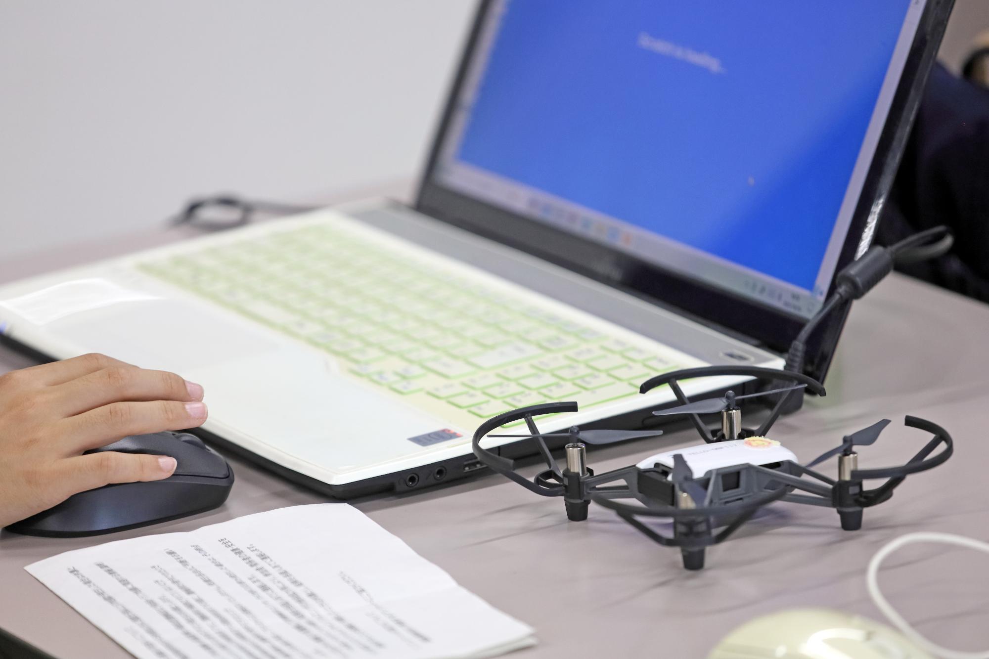 パソコンを使ってドローンにプログラミングを行う写真