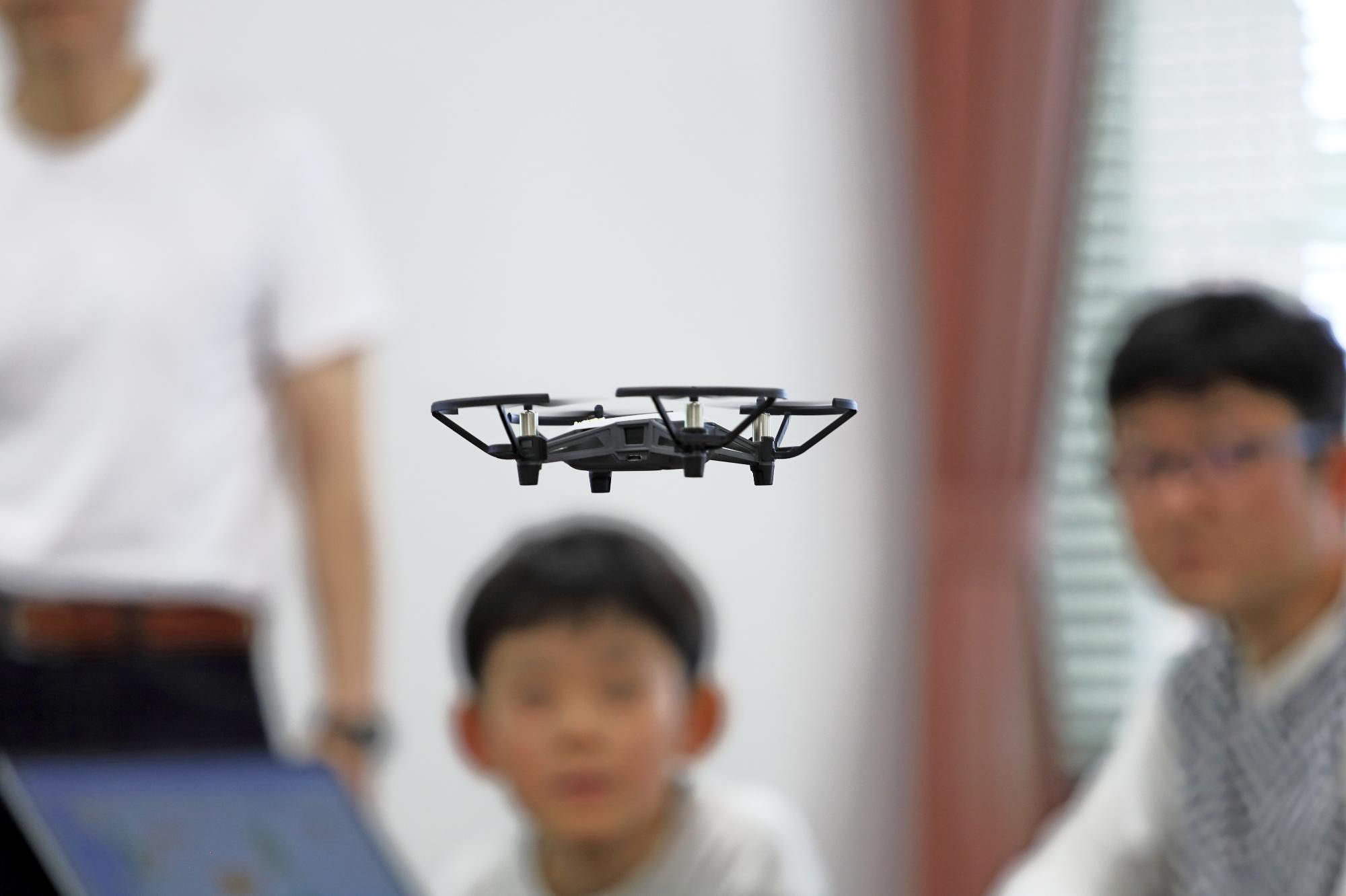 教室内でドローンが宙に浮いて飛行している写真