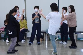 参加者が休憩中に輪になって踊りを練習する写真