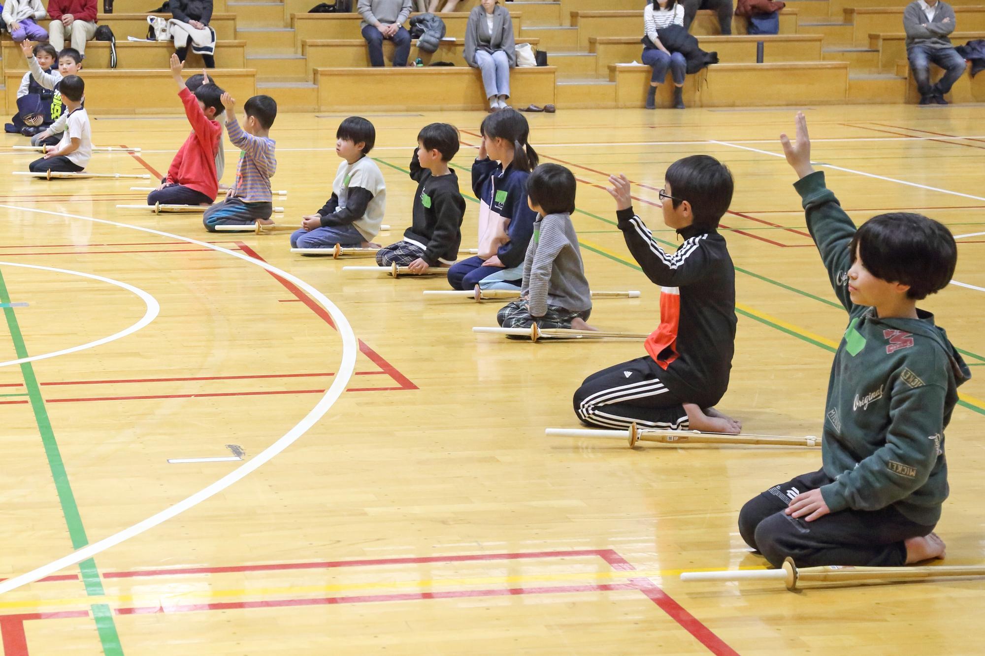 参加者のこども達が正座をしながら手を挙げる写真