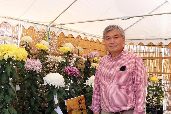 菊の前で立っている男性の写真