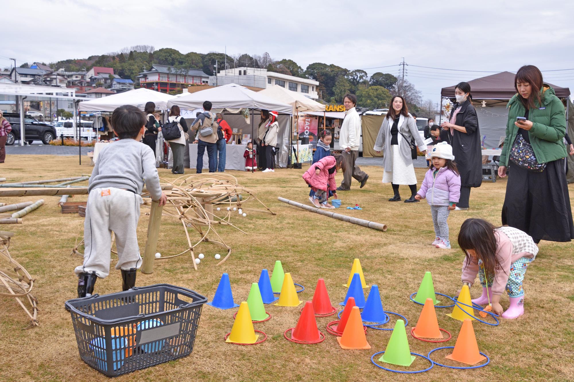 こどもたちやその親が道の駅の芝生広場で遊びを行う様子の写真