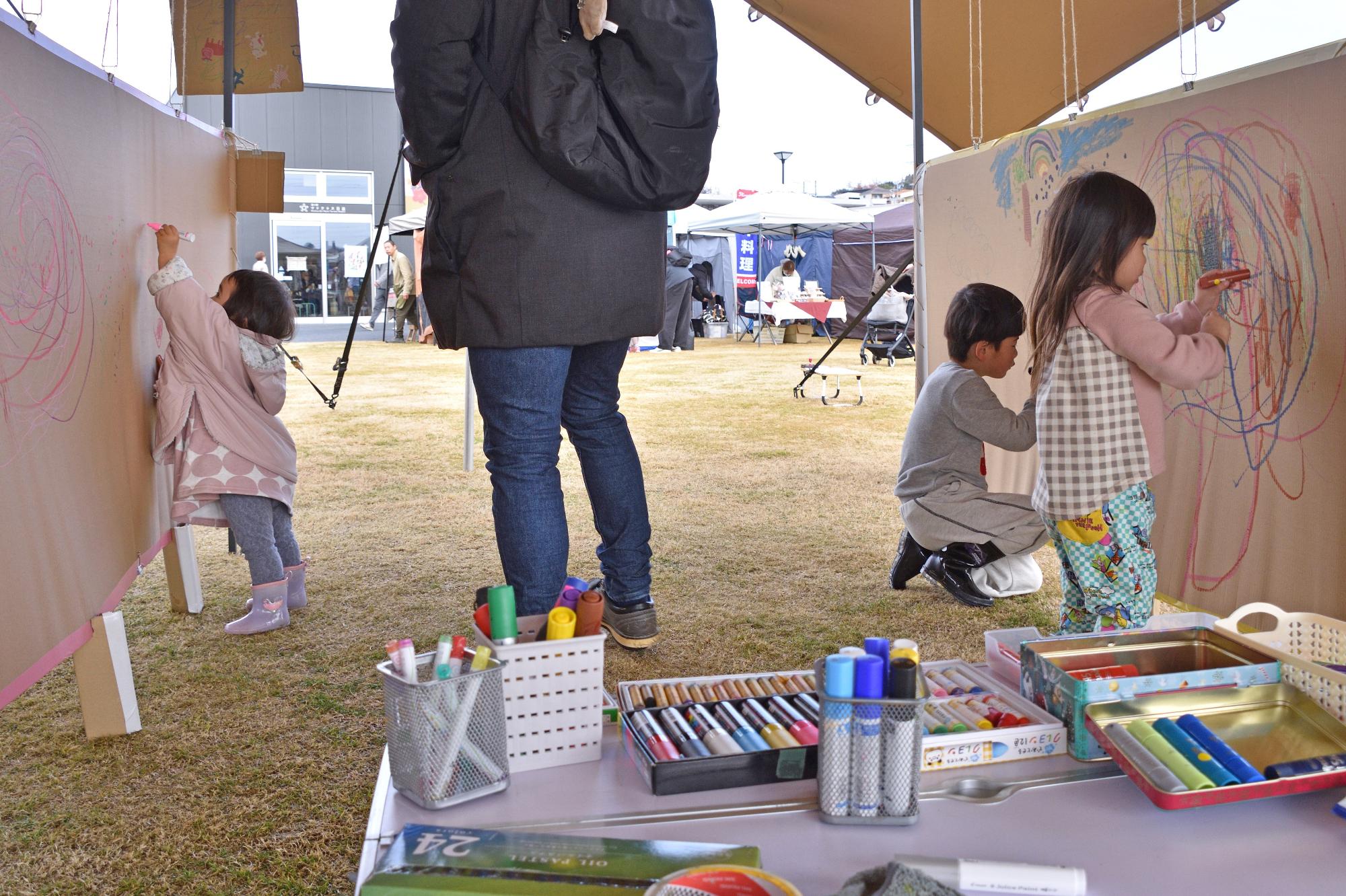 道の駅の芝生広場で開催された落書きスペースに落書きを行うこどもたちの写真
