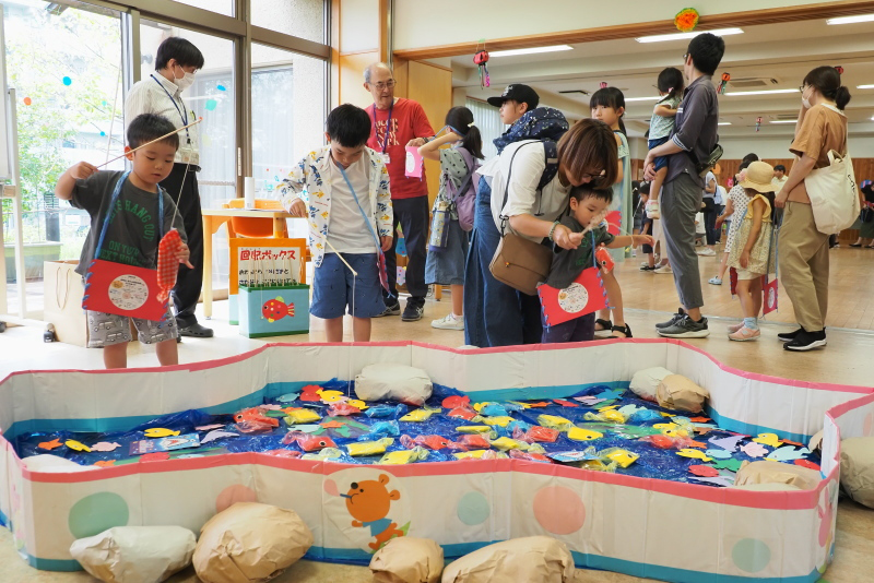 子どもたちが紙製の手作りのさかなつりで遊んでいる写真