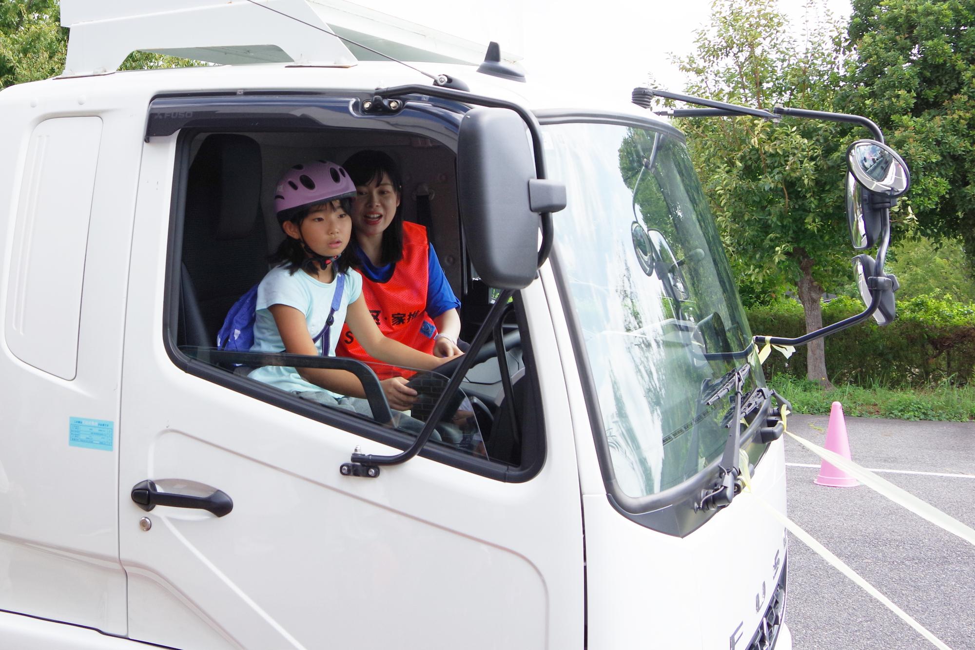 トラックの運転席で説明を受ける子どもの写真