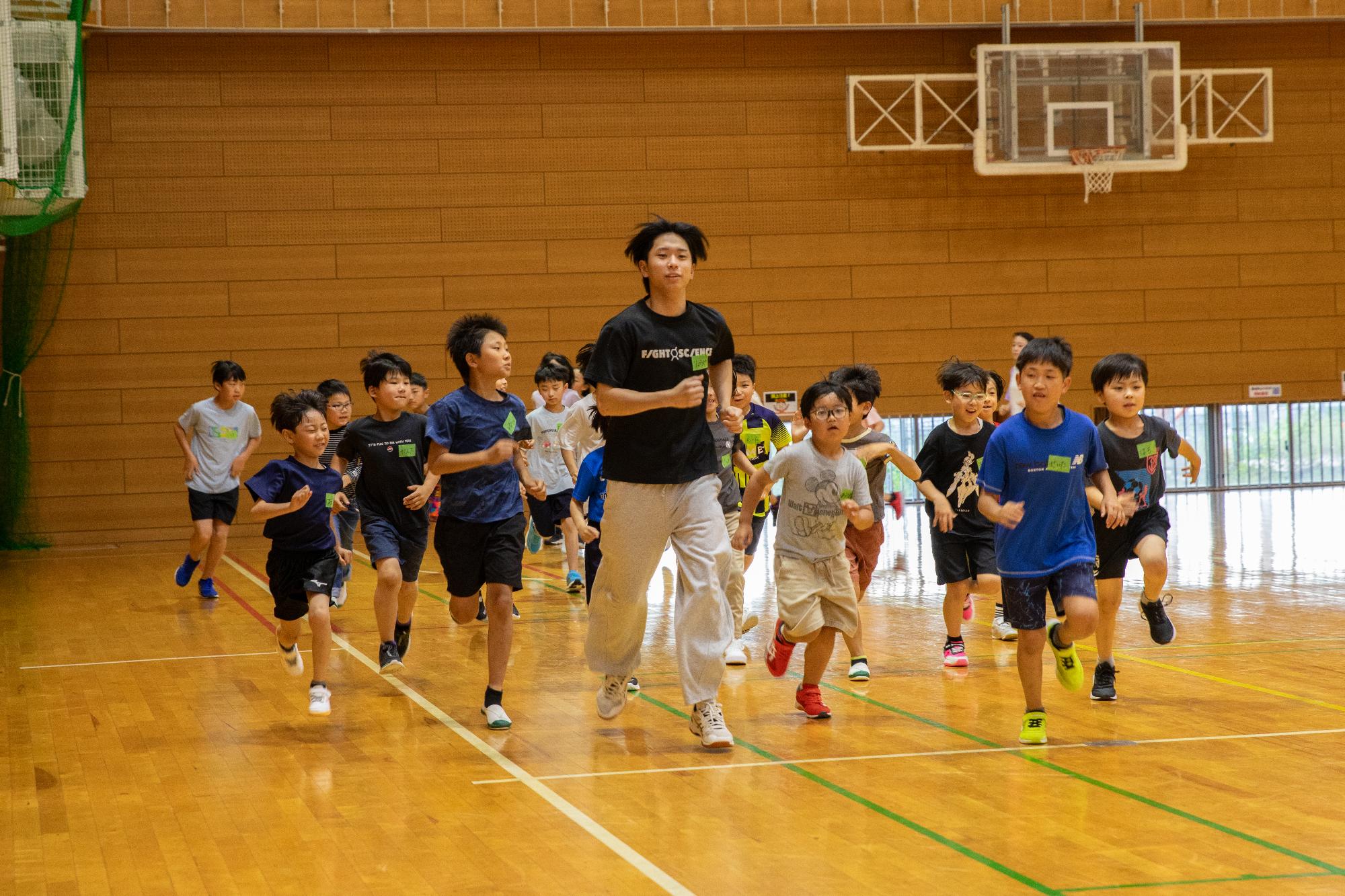 準備運動のランニングを体育館で行っているこどもたちの写真