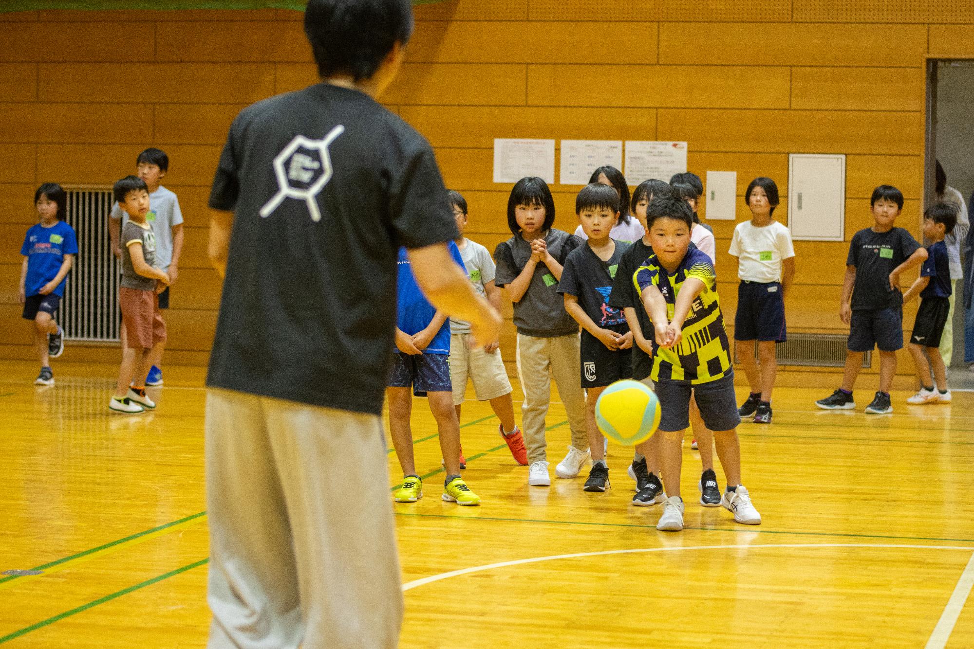 並んでバレーボールの練習をするこどもたちの写真
